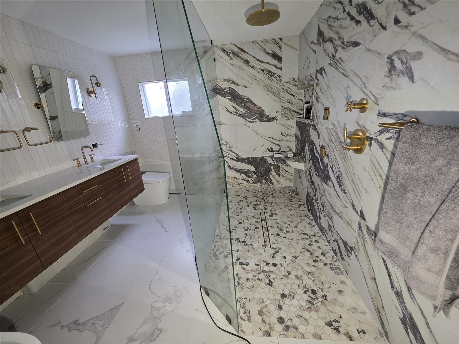 Marble shower surround with hexagon mosaic floor and gold shower fixtures, Tampa Bay, FL