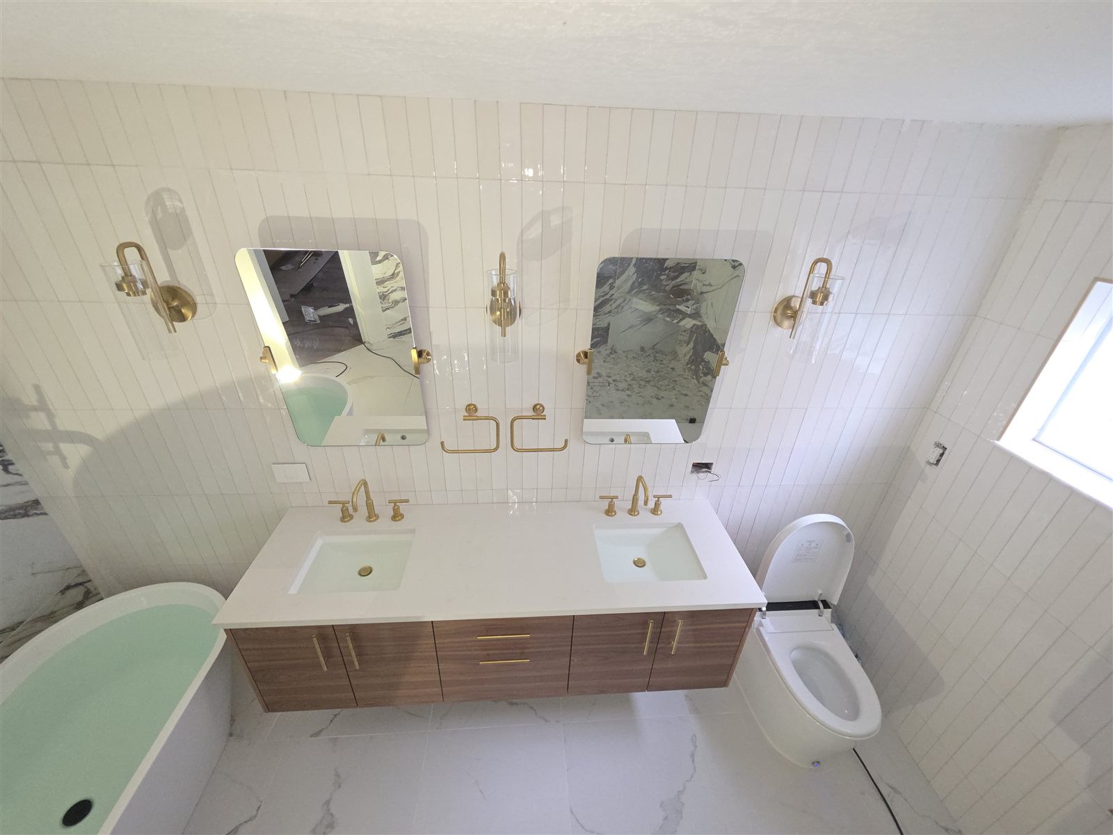 Renovated bathroom with marble tile, double vanity, and freestanding tub, Tampa Bay, FL