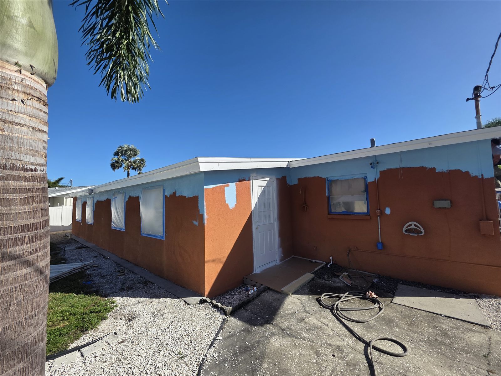 Exterior repaint in progress, stucco home with new blue and white color scheme, Tampa Bay, FL