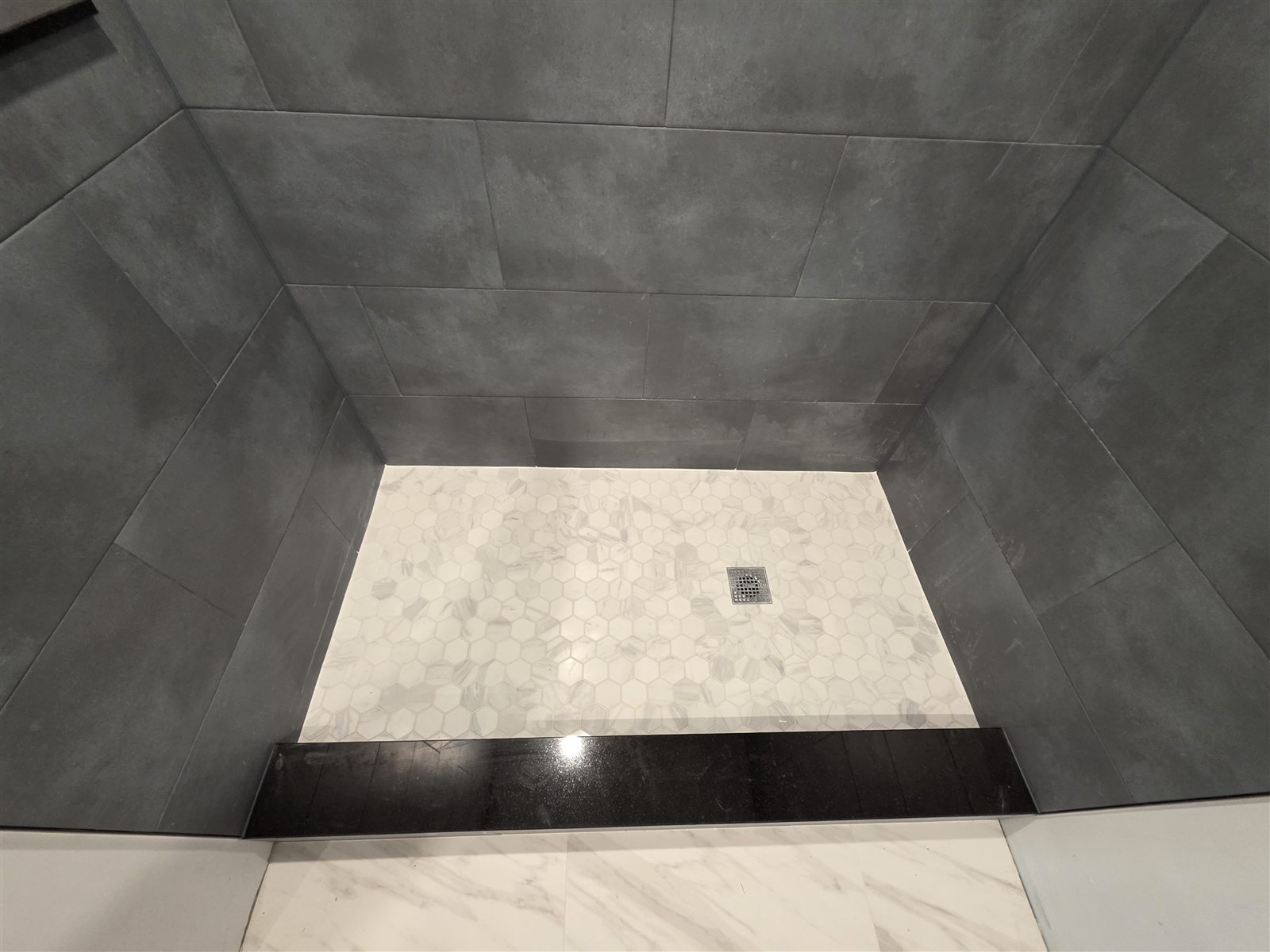 Gray tile shower with white hexagon mosaic floor and black threshold, Tampa Bay, FL